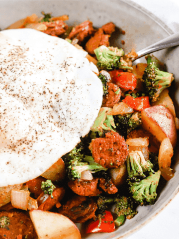 A bowl of chorizo and veggies topped with a fried egg
