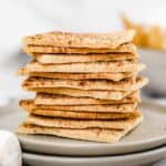 A stack of paleo graham crackers on a stack of grey plates near marshmallows and chocolate