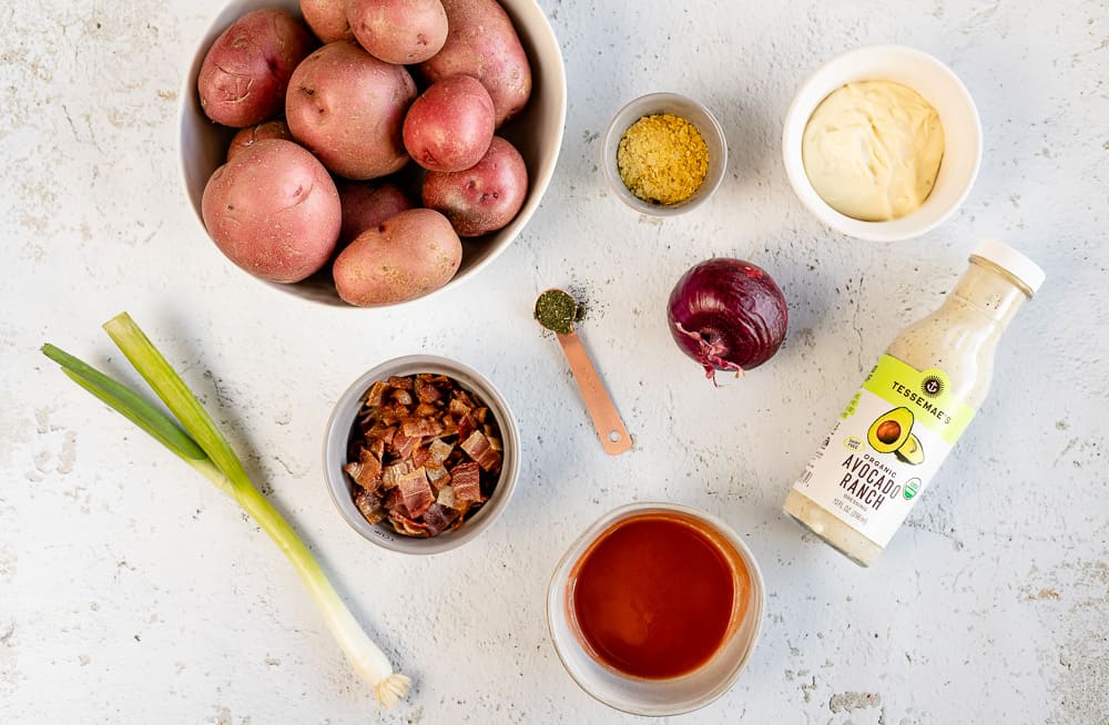 An overview shot of ingredients needed for Buffalo Ranch Potato Salad on a grey background