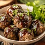 A bowl of baked asian meatballs with whole30 teriyaki sauce on a wood background