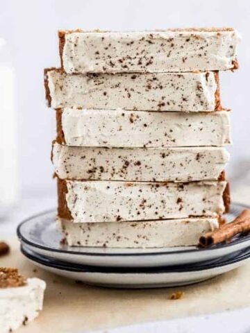 A stack of eggnog bread slices on two plates next to cinnamon sticks