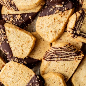 An overview shot of a pile of shortbread cookies dipped and drizzled in chocolate.