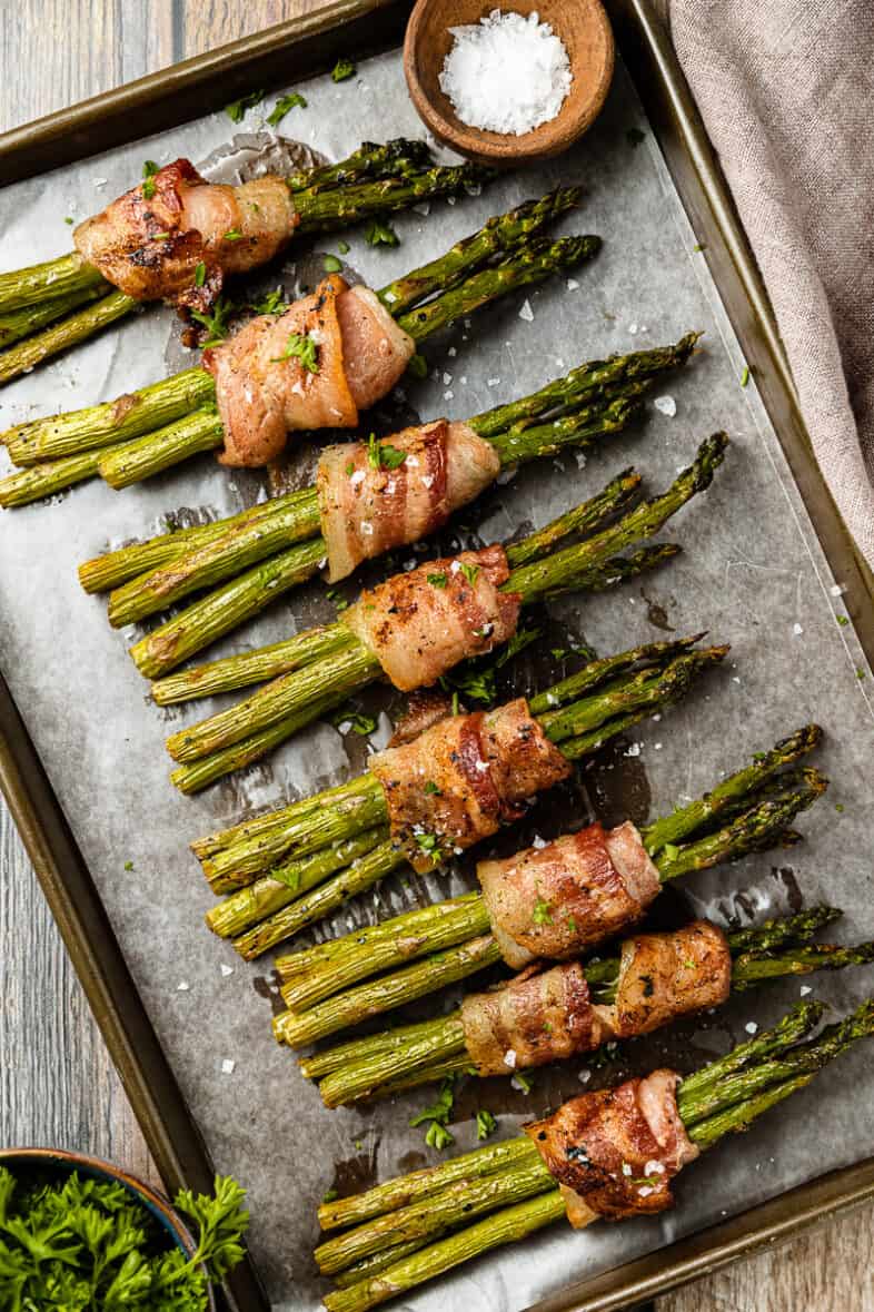 An overhead shot of a pan full of grilled bacon wrapped asparagus bundles.