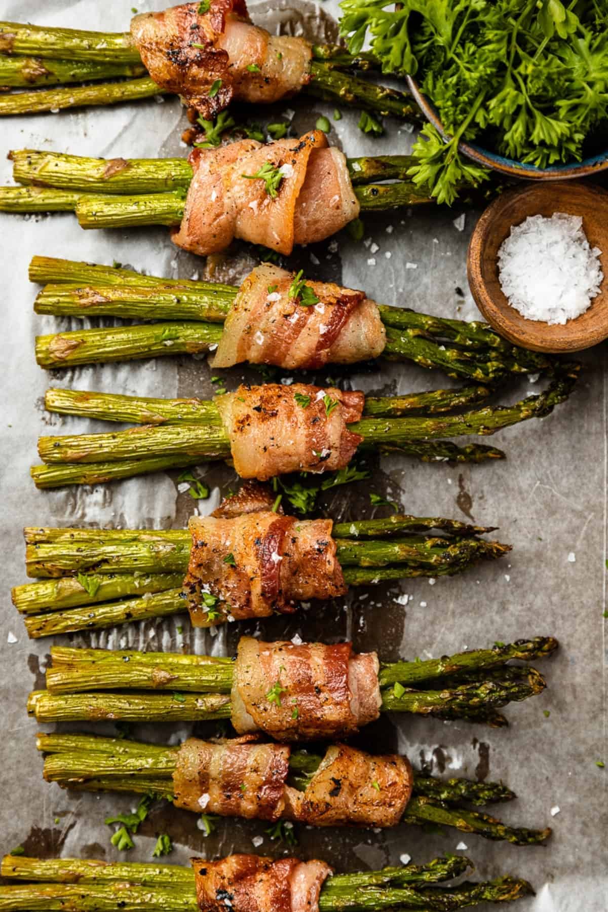 An overhead shot of a pan full of grilled bacon wrapped asparagus bundles.