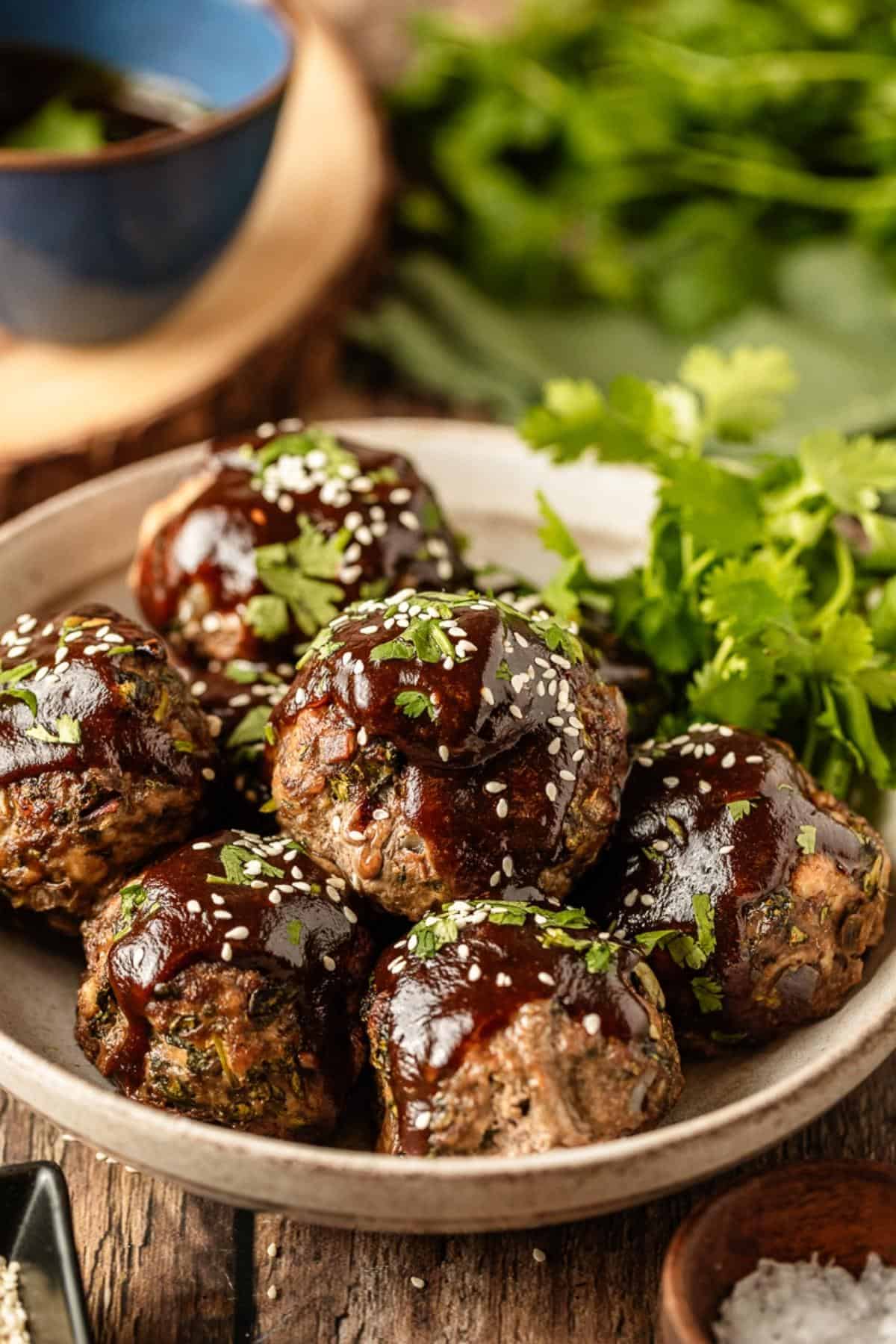A bowl of baked asian meatballs with whole30 teriyaki sauce on a wood background