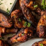 An overview shot of dry rub chicken wings topped with parsley and served with ranch.